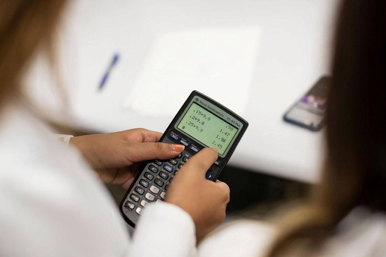 A student entering equations into a calculator.