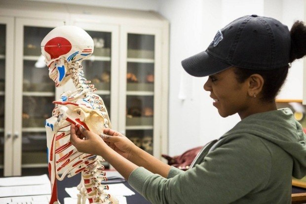 A student handling a plastic skeleton.