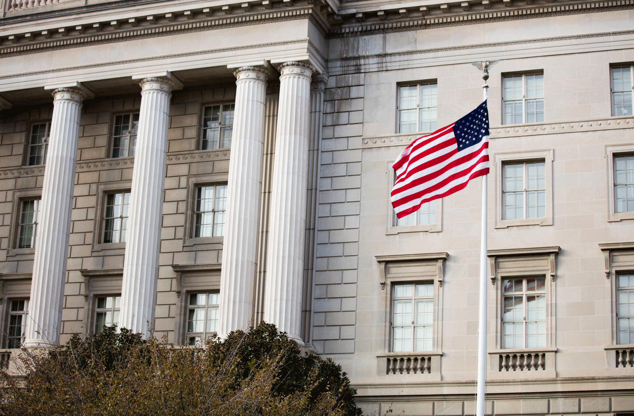The American flag raised in front of a white building in Washington, DC.
