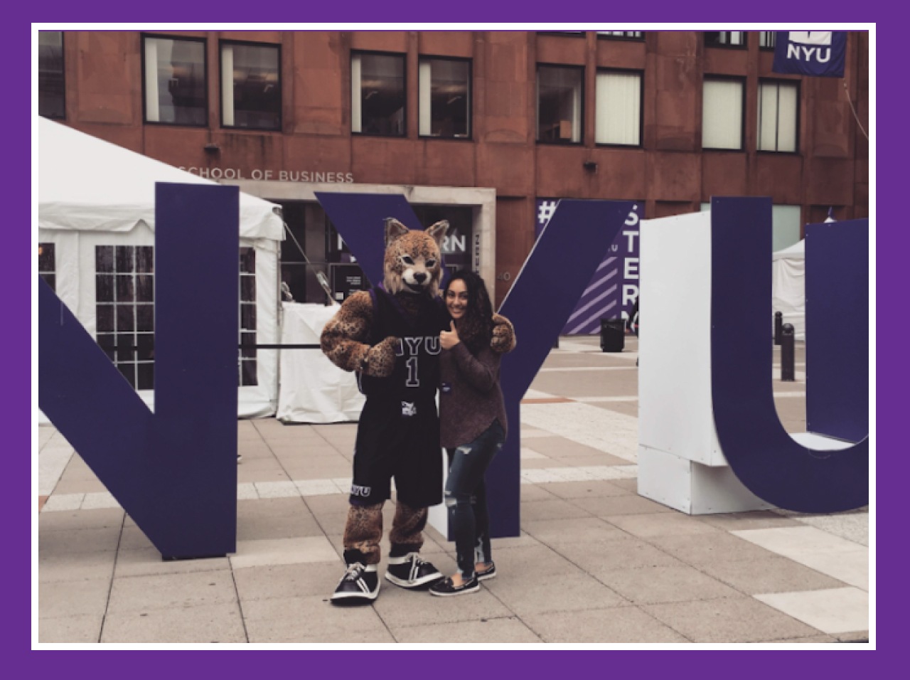 Yasmine posing with the NYU mascot in front of large block letters that read “NYU.”