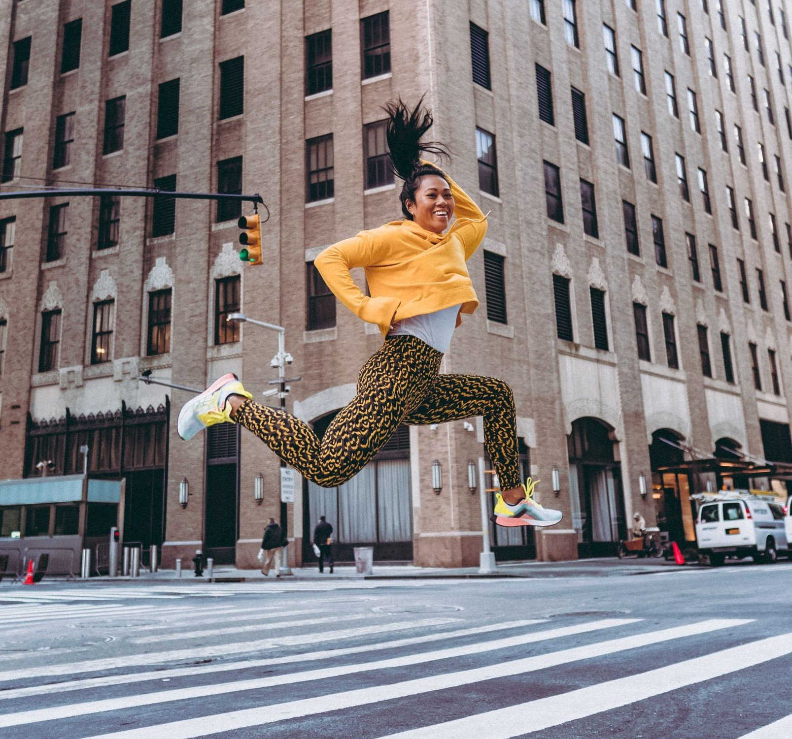 A dancer smiling in midair of a New York City street.