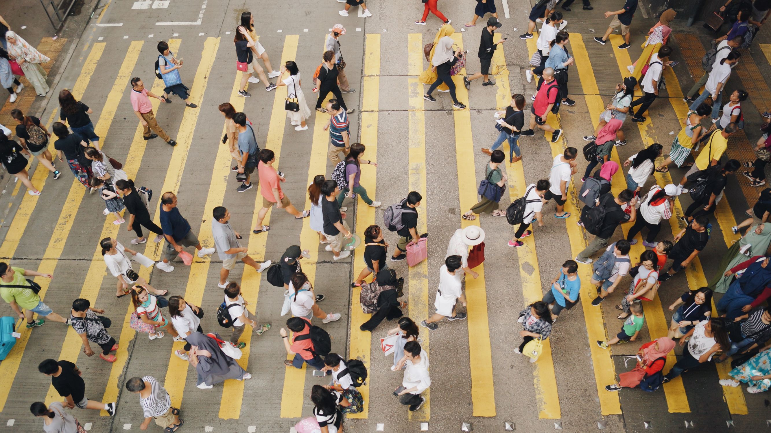 A crowd of people at a yellow crosswalk.
