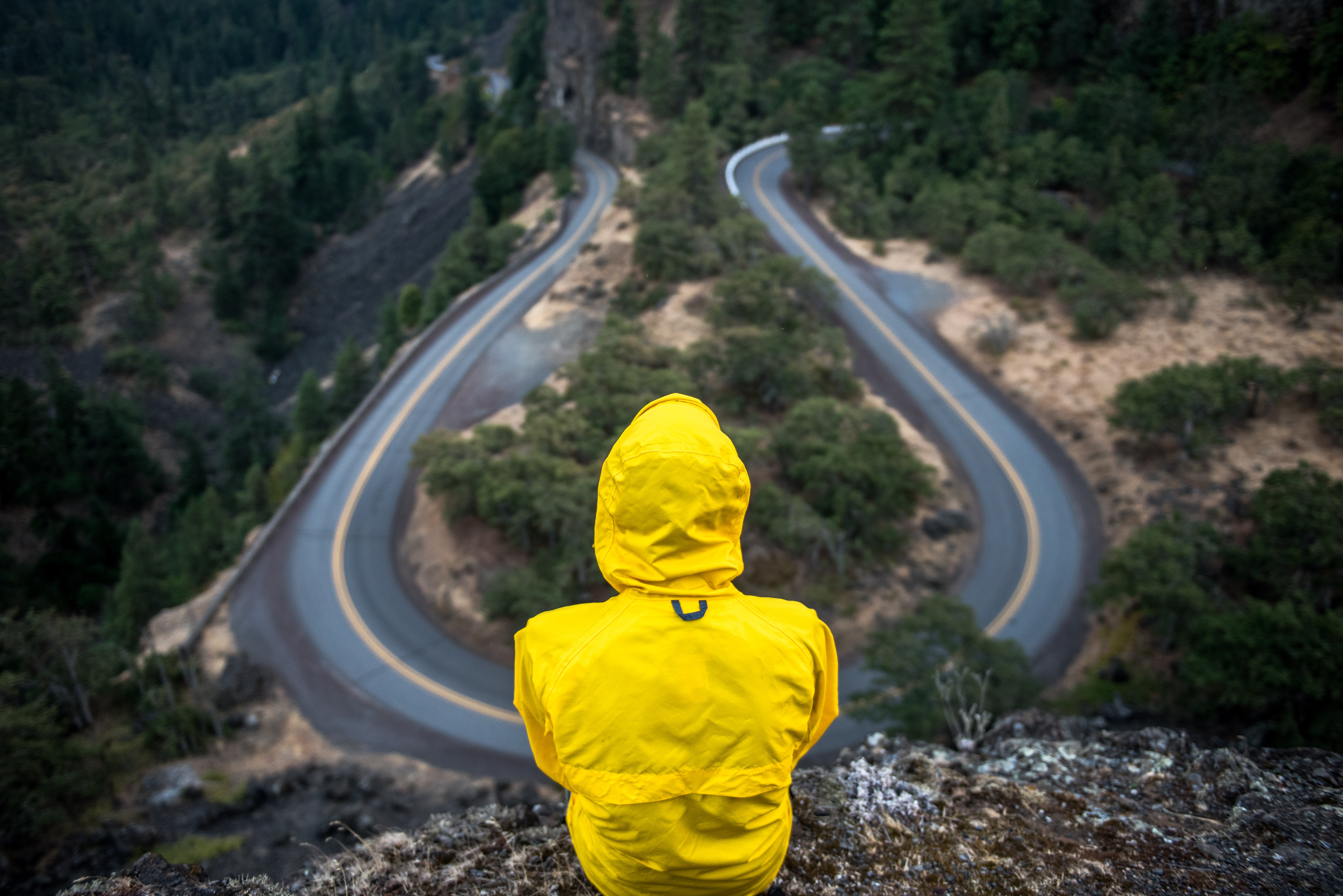 A person in a yellow jacket looking at two roads.