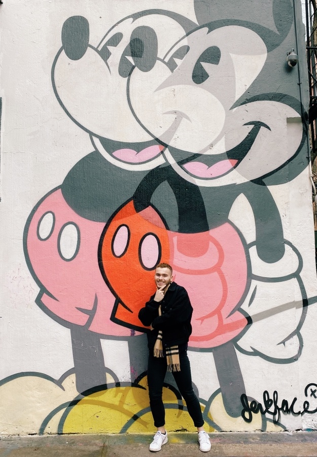 Zach, the author, posing in front of a graffitied Mickey Mouse.