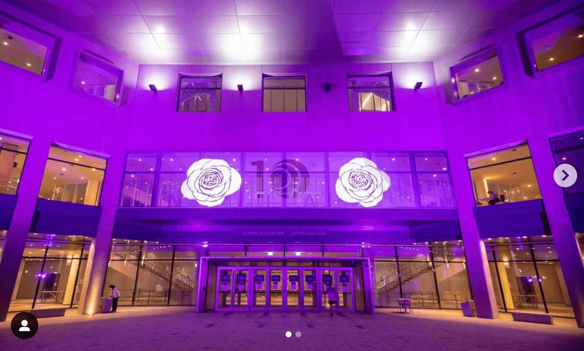 Photo of NYU Abu Dhabi campus that is illuminated in purple lighting