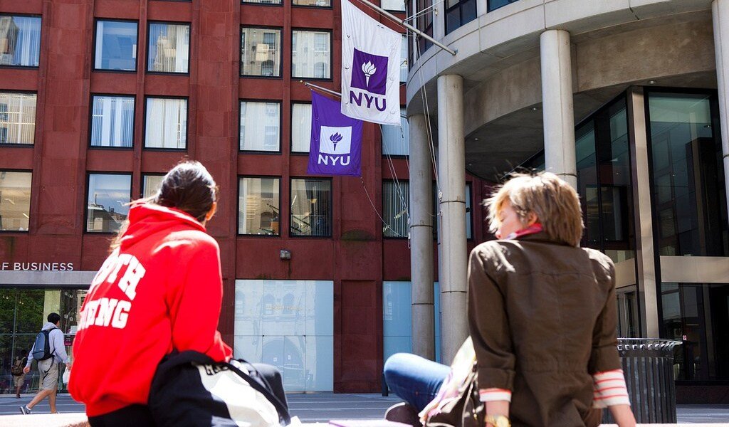 Students sitting in front of the NYU Stern building.
