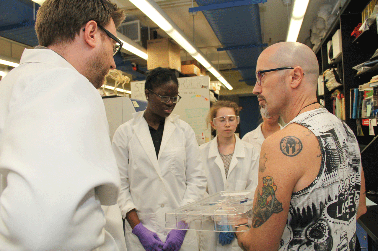 A group of students and a professor looking a lab equipment