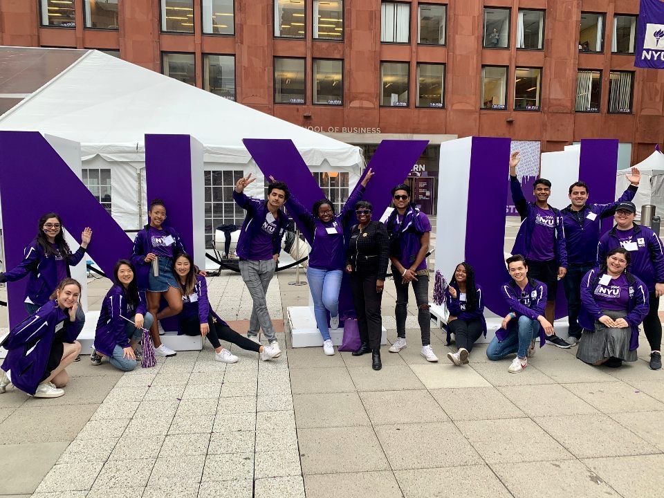 NYU students in front of large letters spelling “NYU.”