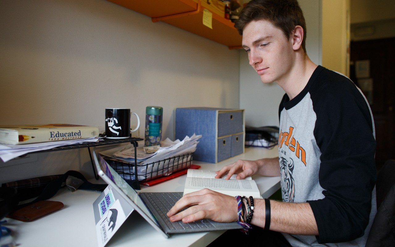 A Sport Broadcasting student working in their dorm room on a laptop.