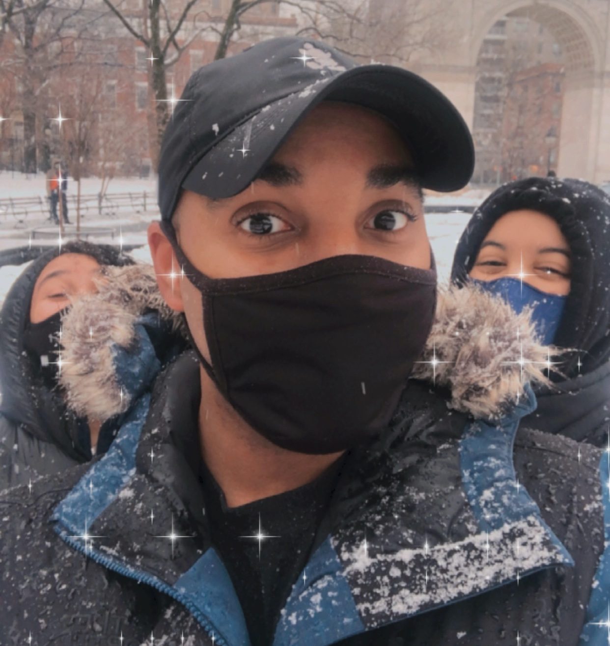 Three masked NYU students in the snow in Washington Square Park.