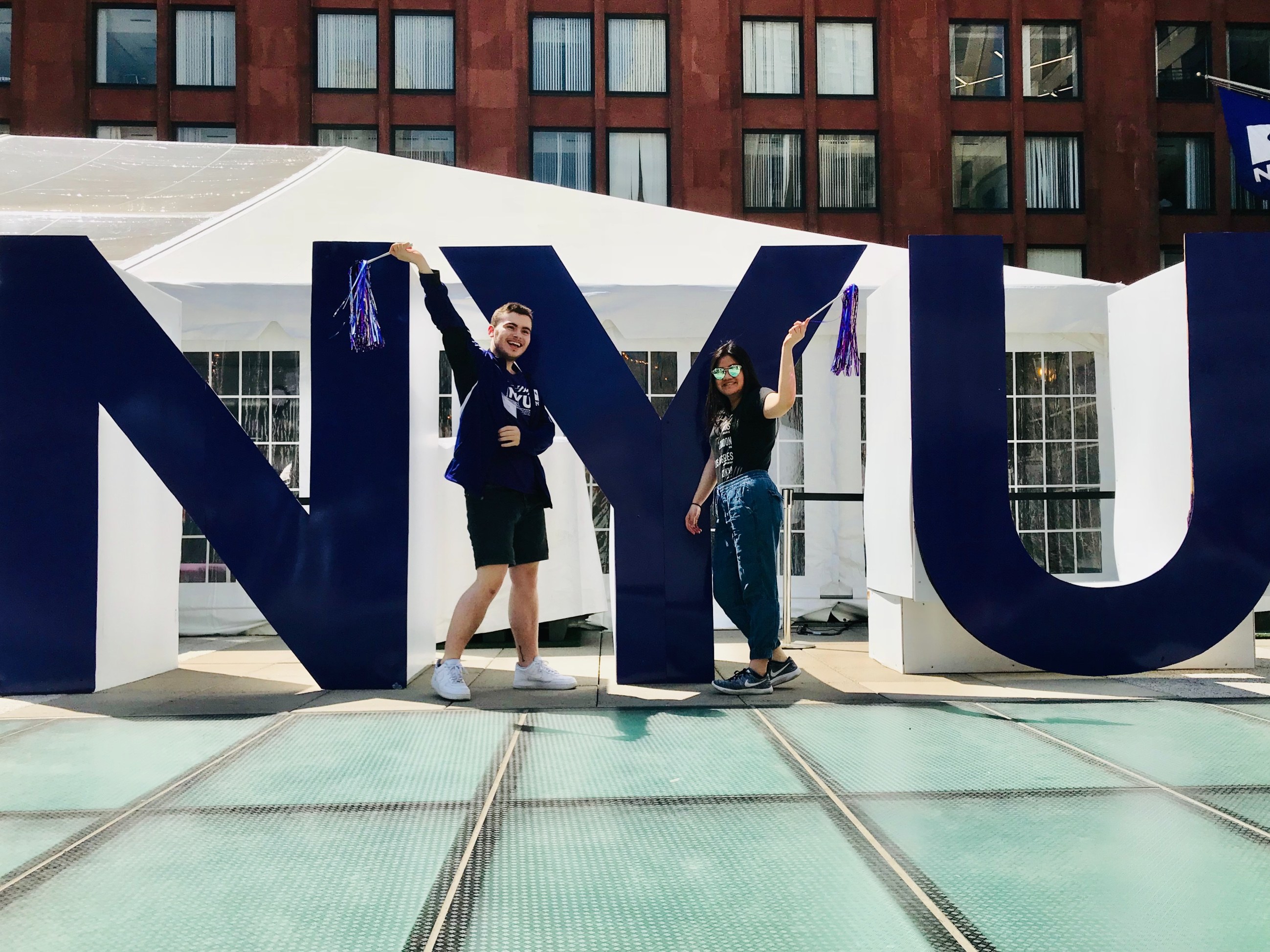 NYU students posing in front of large NYU letters.