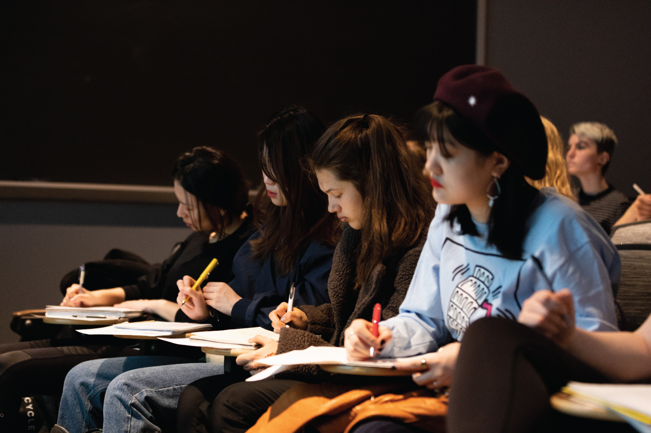 A row of students taking notes in class.