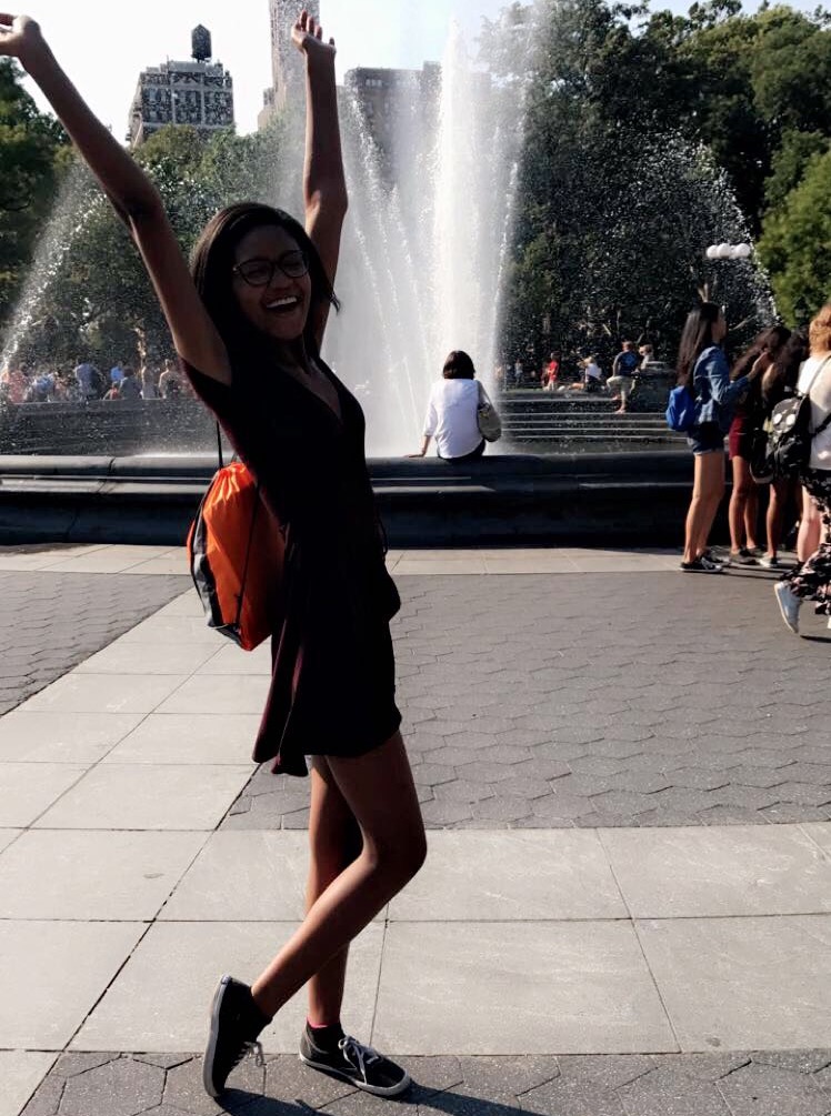 The author standing in front of Washington Square Park with her arms up.