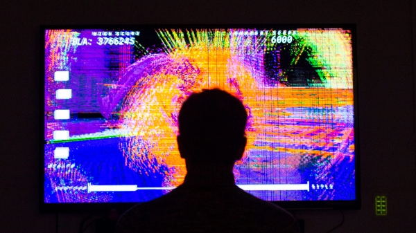 A person looking at a screen playing an abstract film