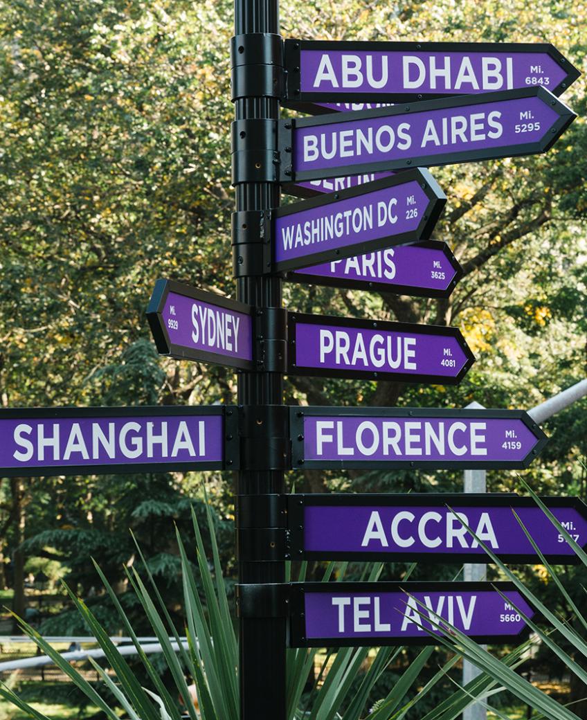 A signpost pointing to the NYU global academic locations.