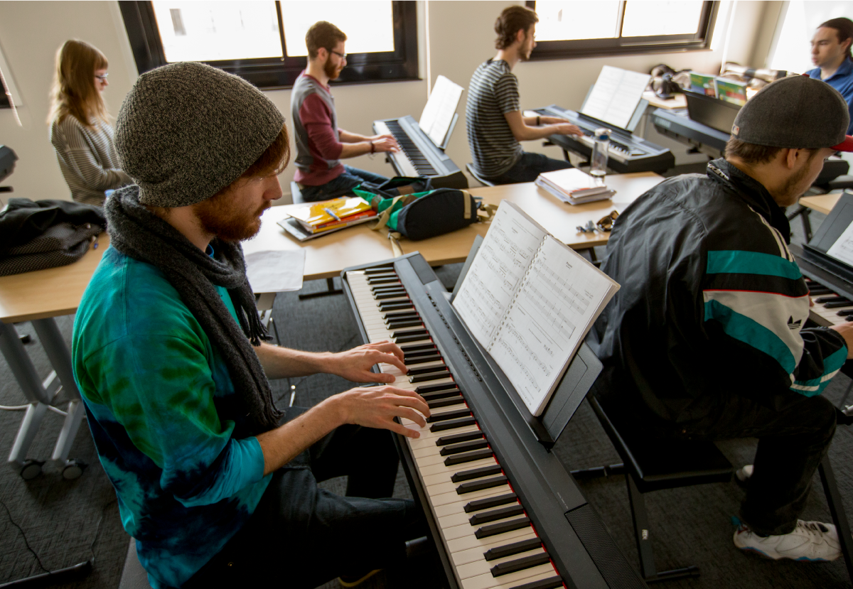 A group of students playing keyboards in a classroom.