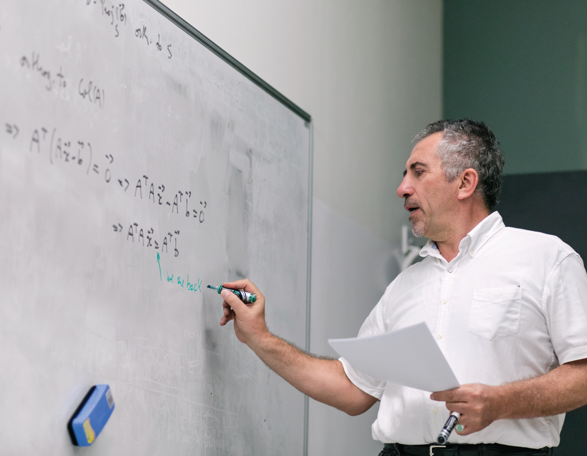 A professor writing an equation on a whiteboard.