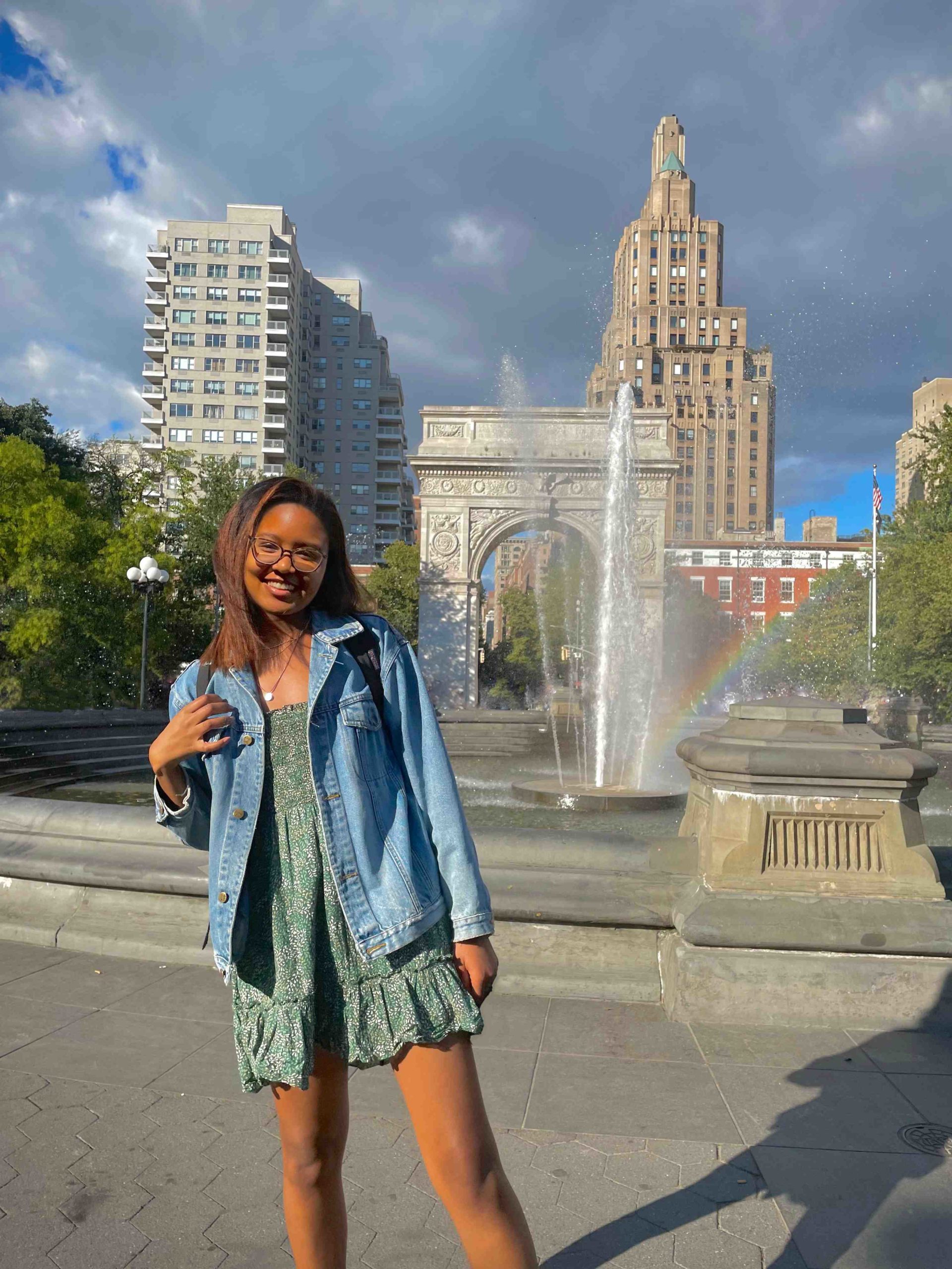 NYU student in front of the Washington Square fountain and arch at NYU.