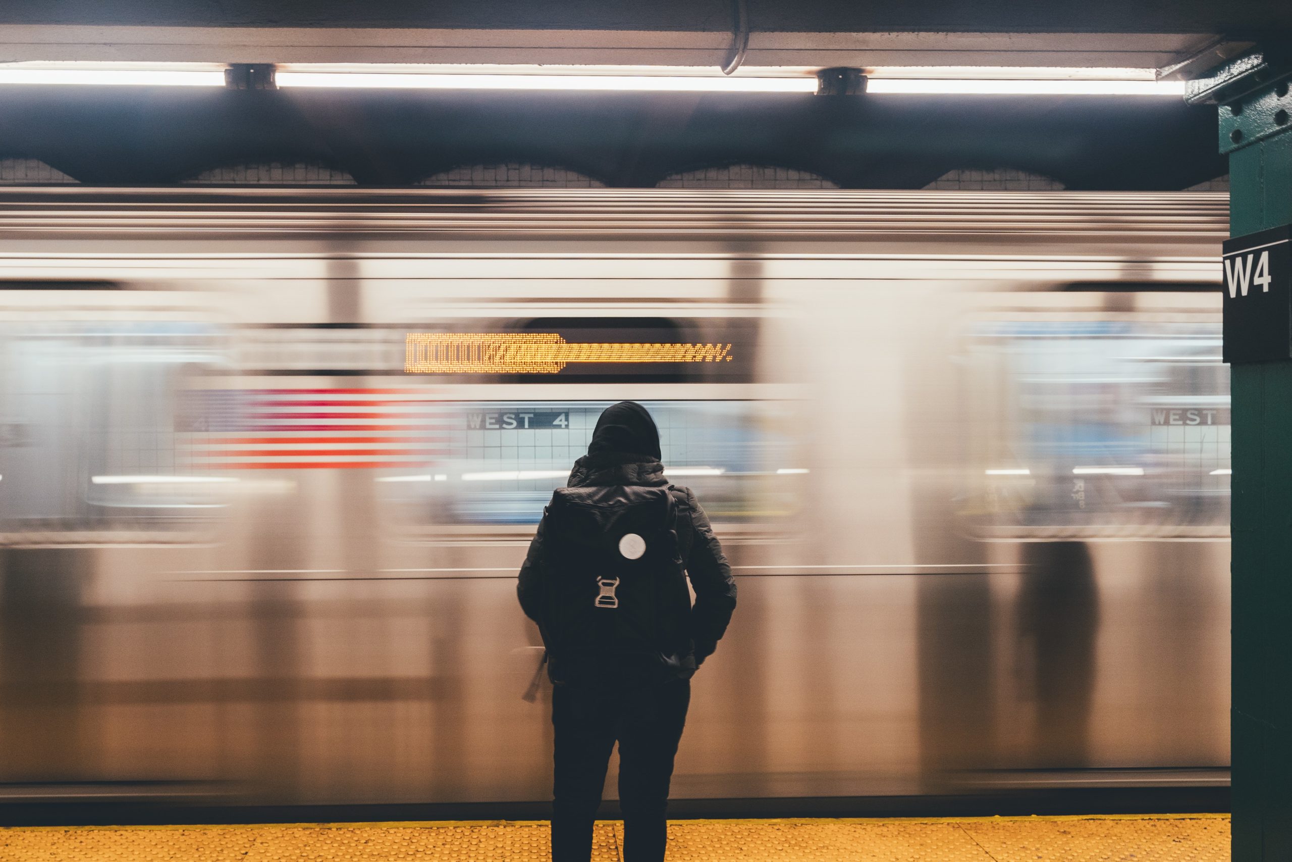 A subway car whizzing by a student waiting on the platform.