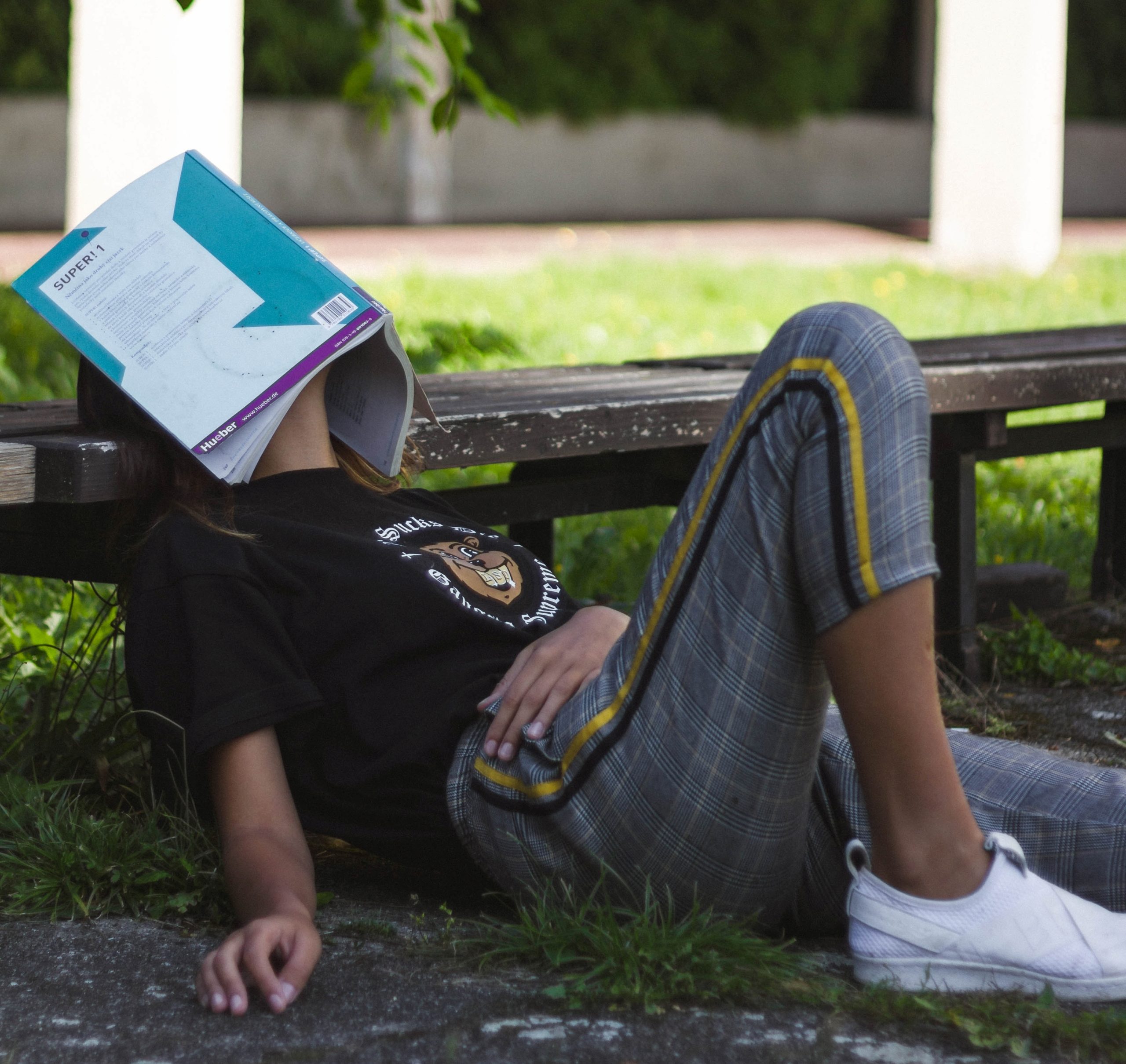 A student lying down with a book covering their face.