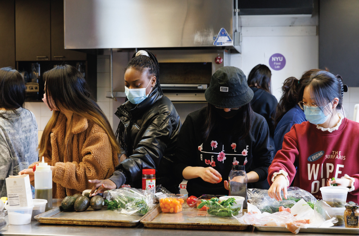 A group of students assembling their food presentations with ingredients available on a table.