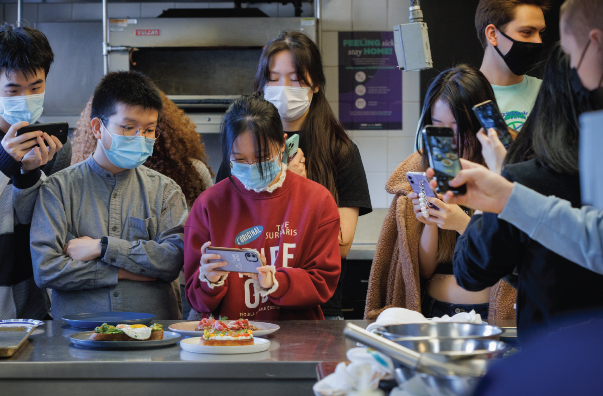A group of students taking photos of a food presentation.