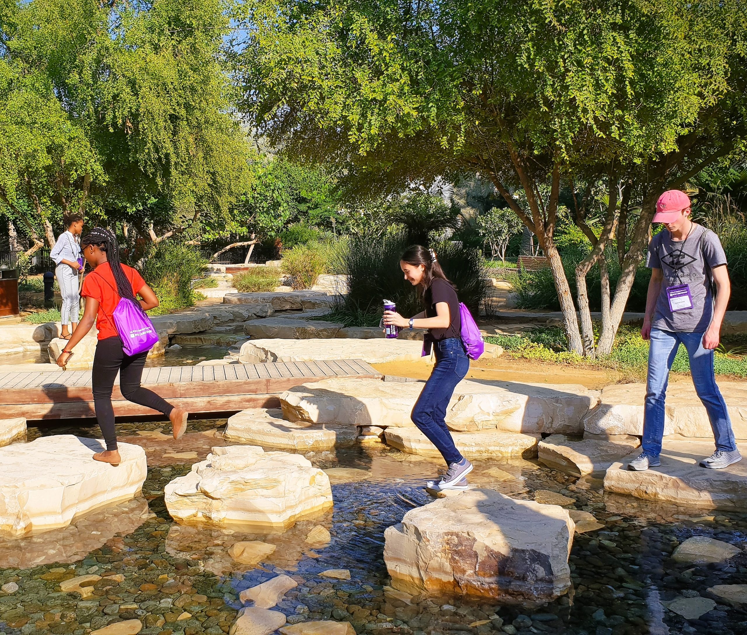 Students walking on rocks in water.
