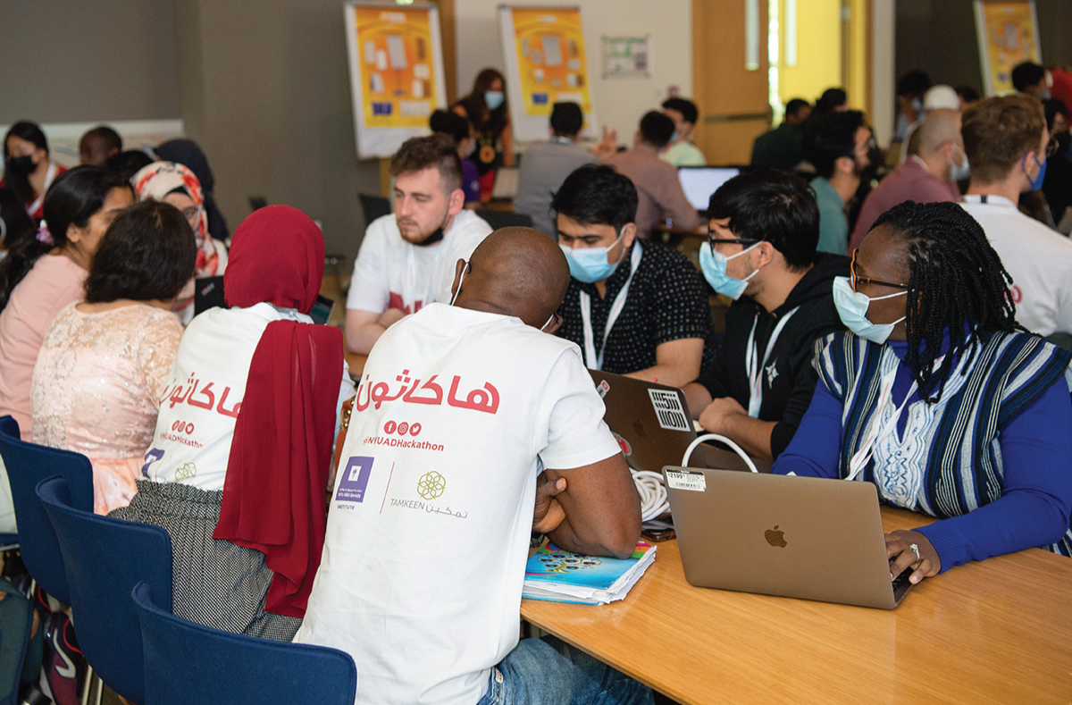 NYUAD International Hackathon for Social Good participants sitting at a long table.