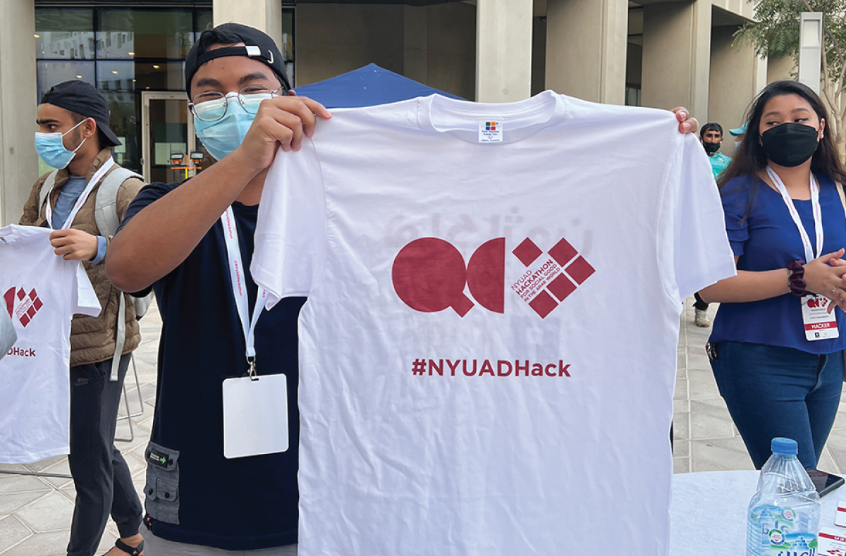 A student holding up a branded hackathon T-shirt.