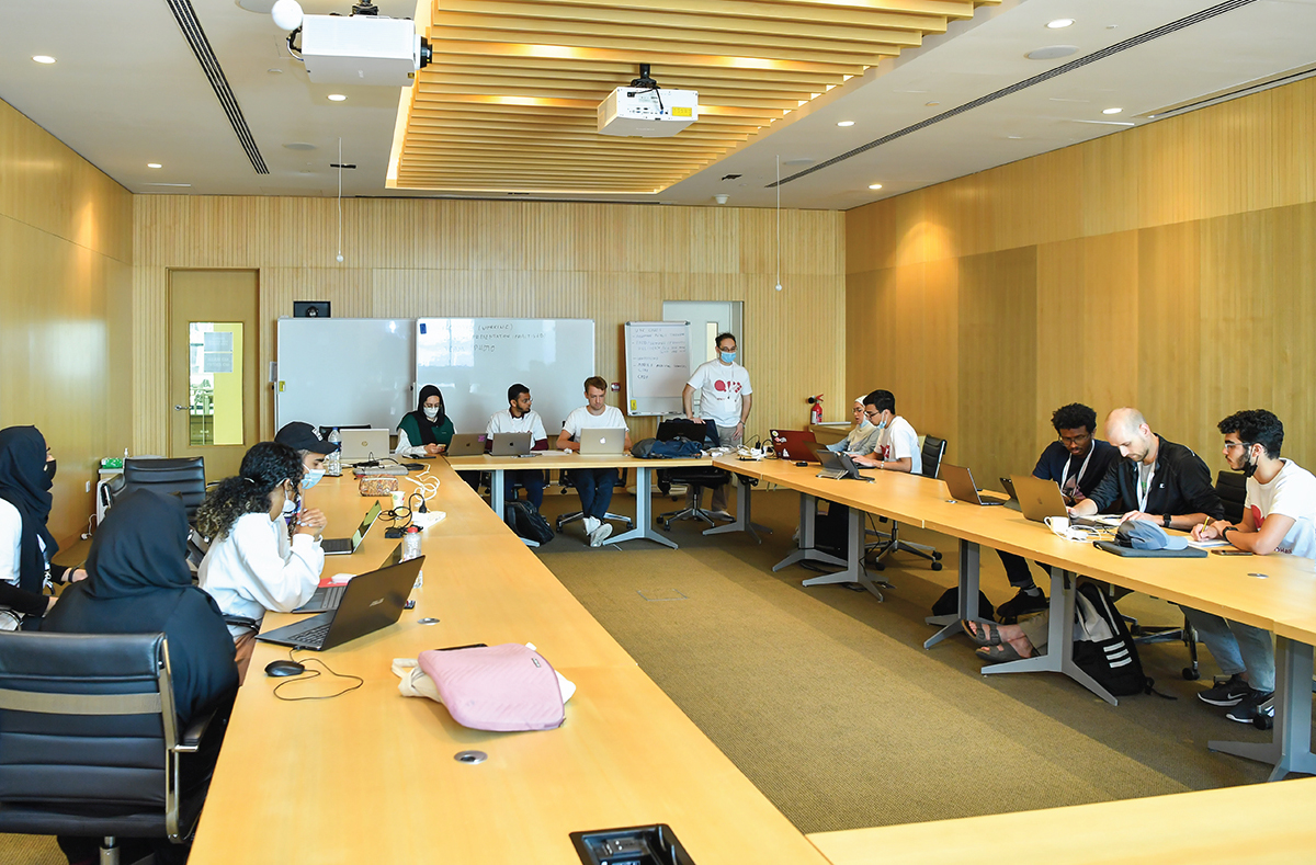 A wide angle view of a group of students working in a conference room.