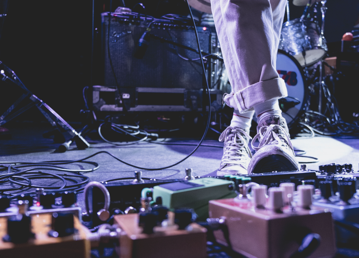 A close-up of a musician stepping on a guitar pedal.