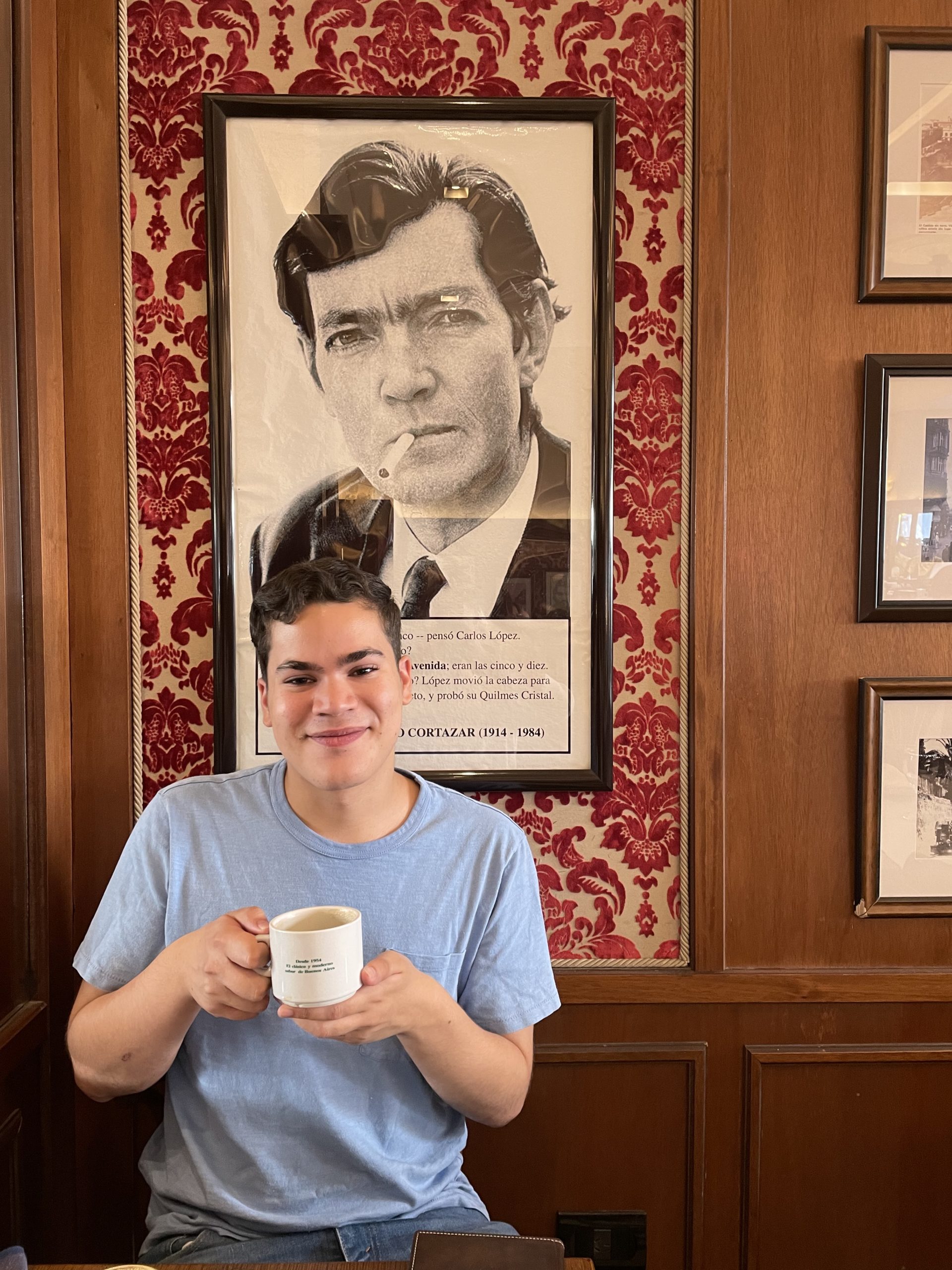 Me drinking coffee in front of a picture of Julio Cortazar