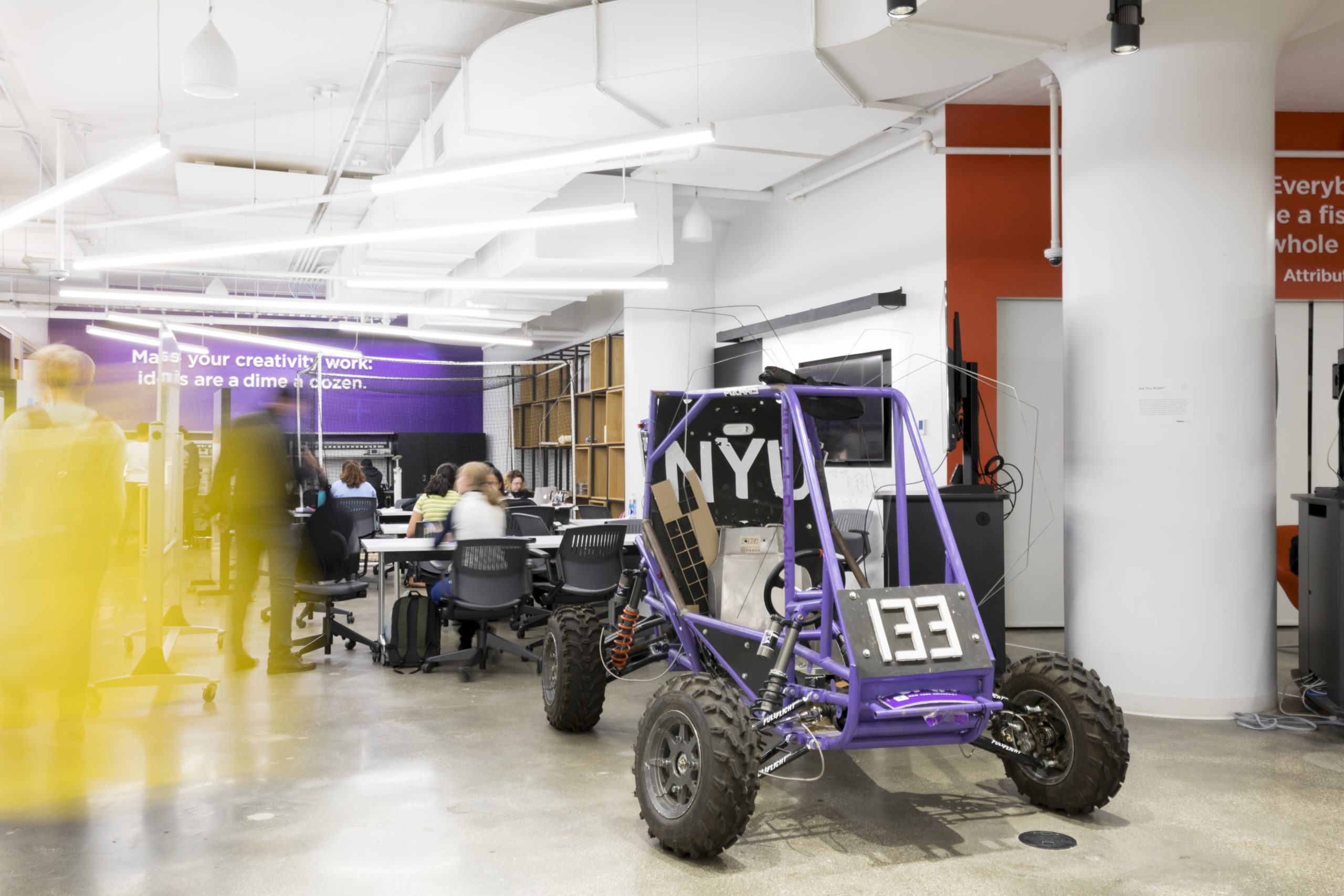 A purple off-road vehicle sits in the middle of the workshop floor at the NYU Tandon MakerSpace.