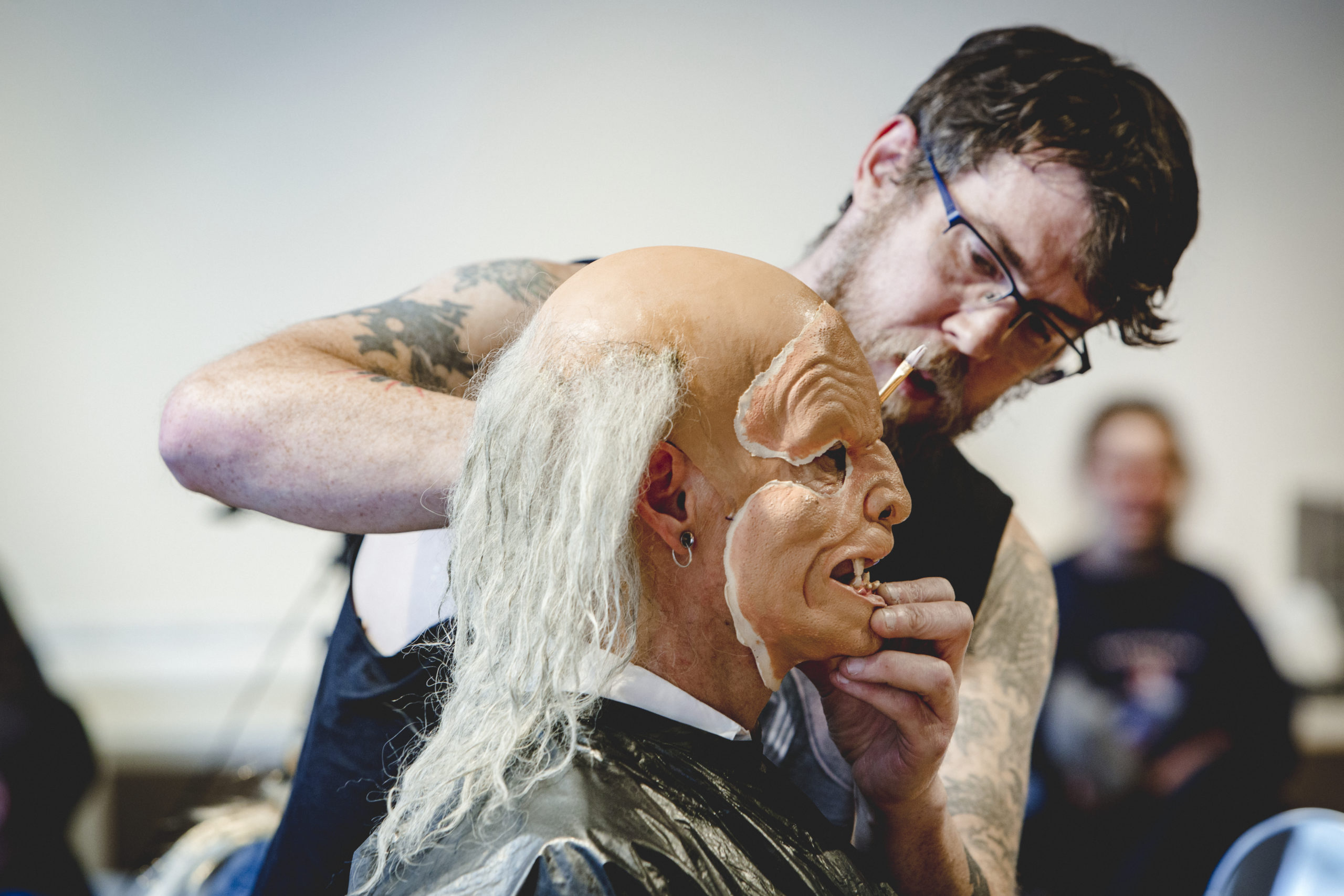 An artist working on special effects makeup on a model