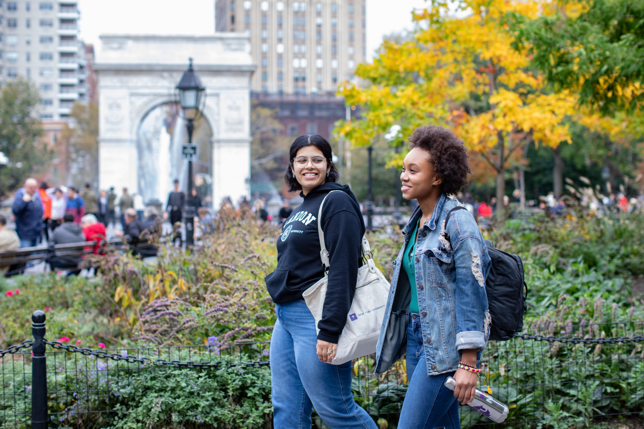 Two students walking through Washington Square Park.