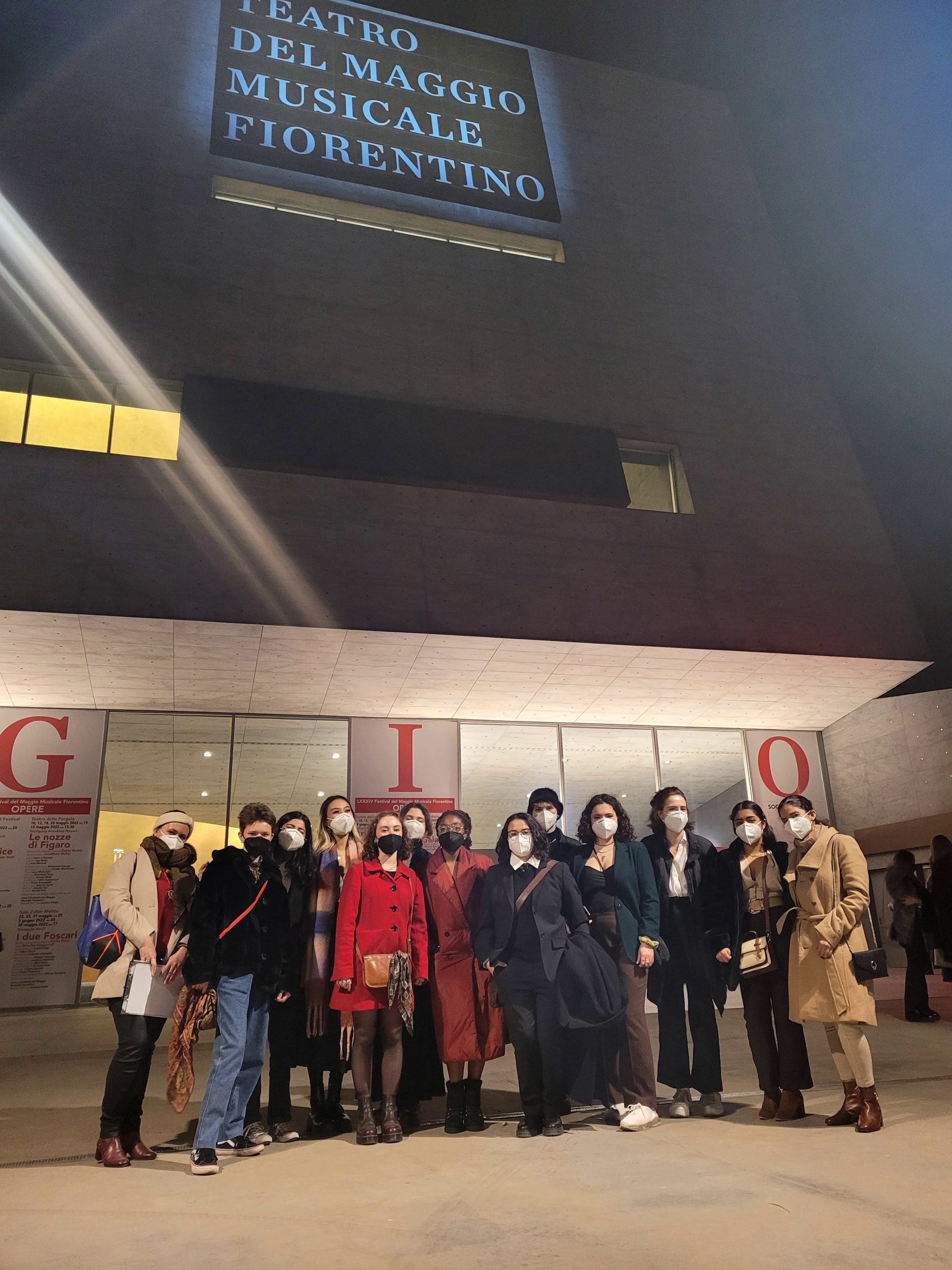 Group photo of NYU Florence students in front of an opera theatre at night.