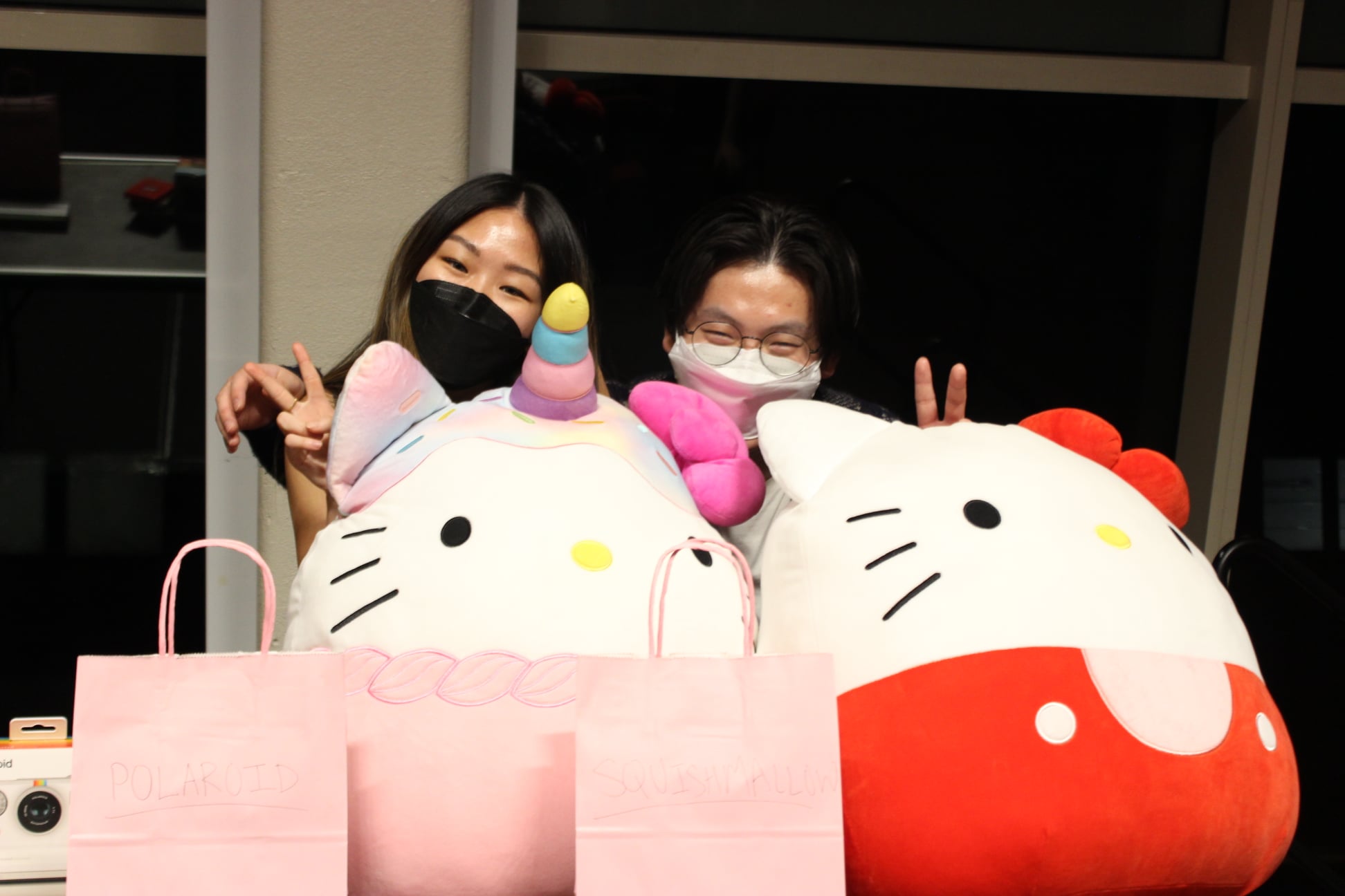 Two students smiling behind two large Hello Kitty figures.