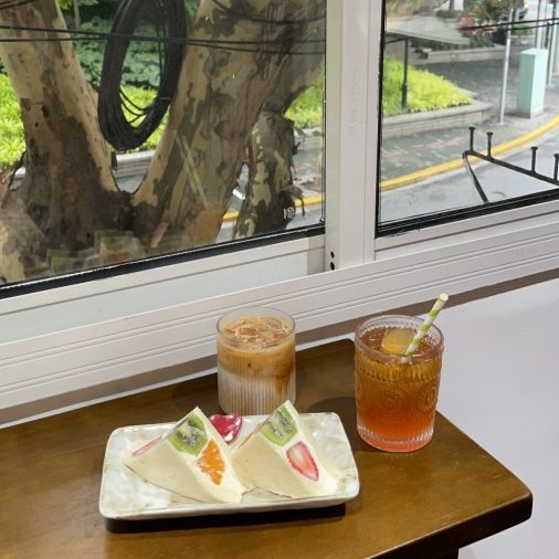 Fruit sandwiches and cold tea in front of a window sill on a sunny day.
