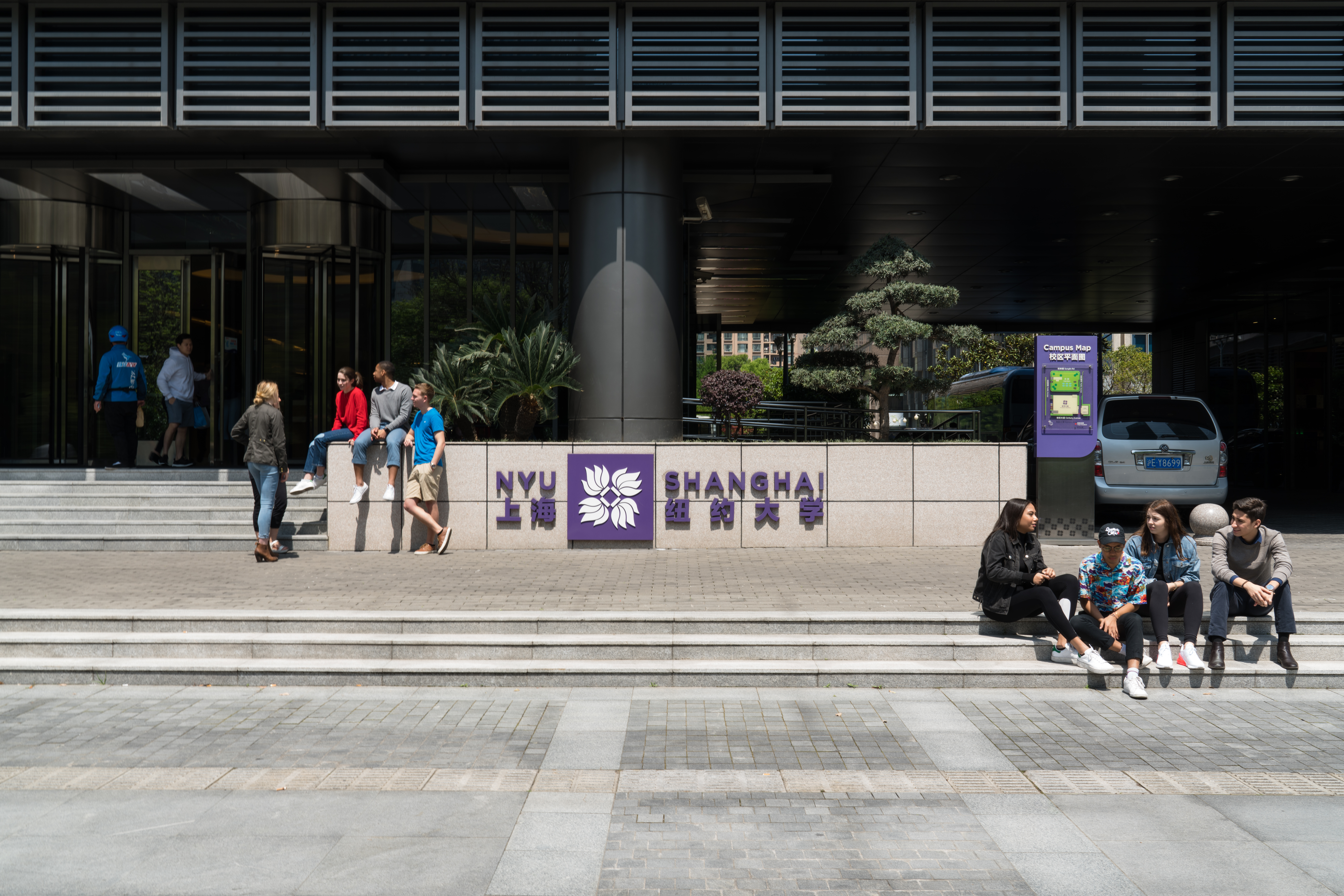 Students sitting in front of the entrance of the former NYU Shanghai academic building.
