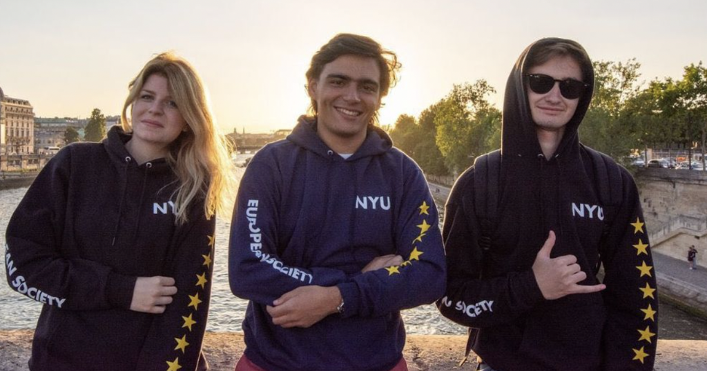 Three students posing with European flag sweatshirts that say “NYU”