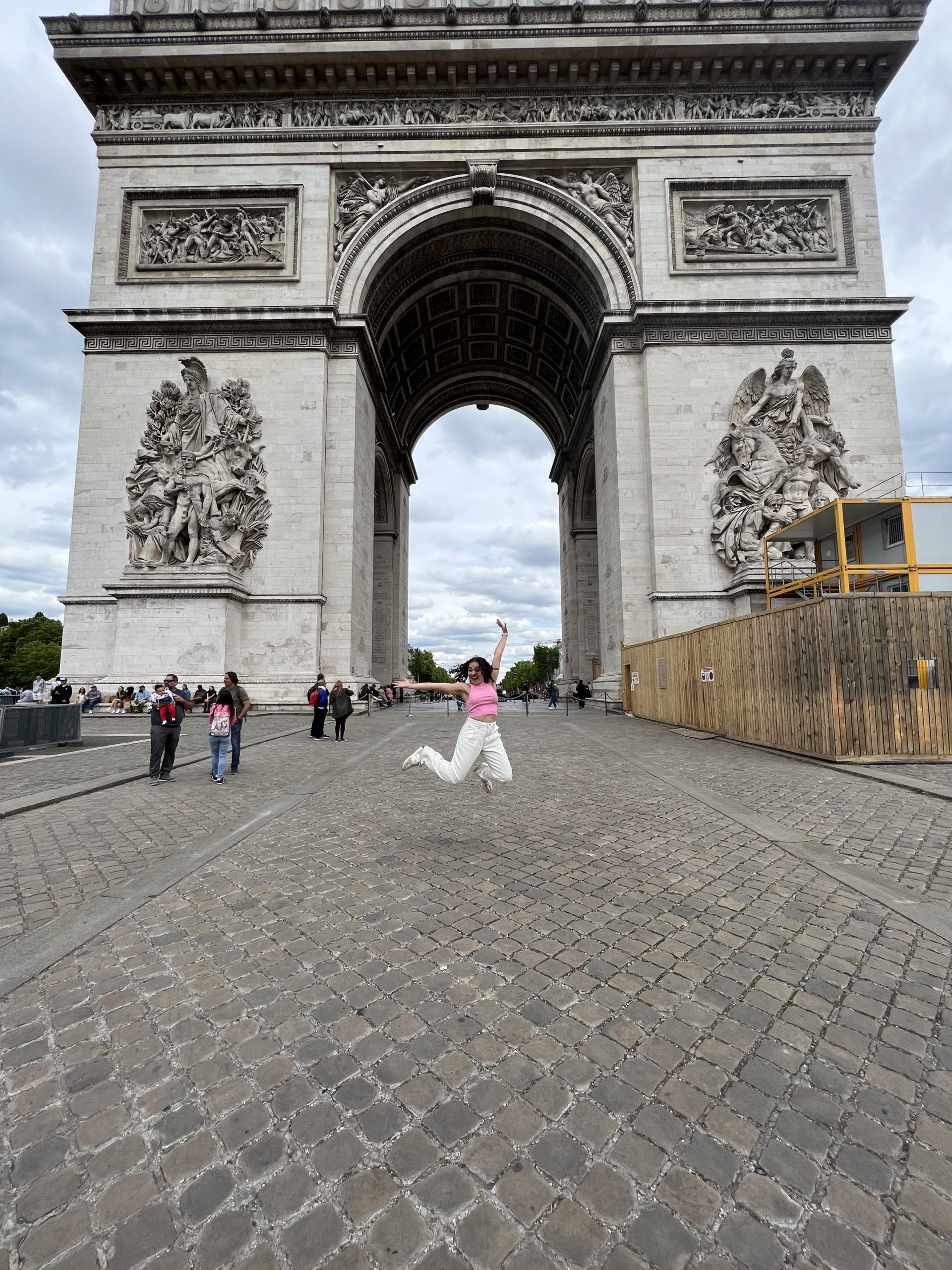 Girl jumping in front of Arc de Triomphe, Paris, France