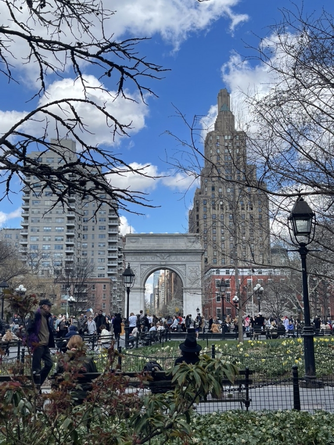 Washington Square Park in early spring with a clear blue sky and clouds.