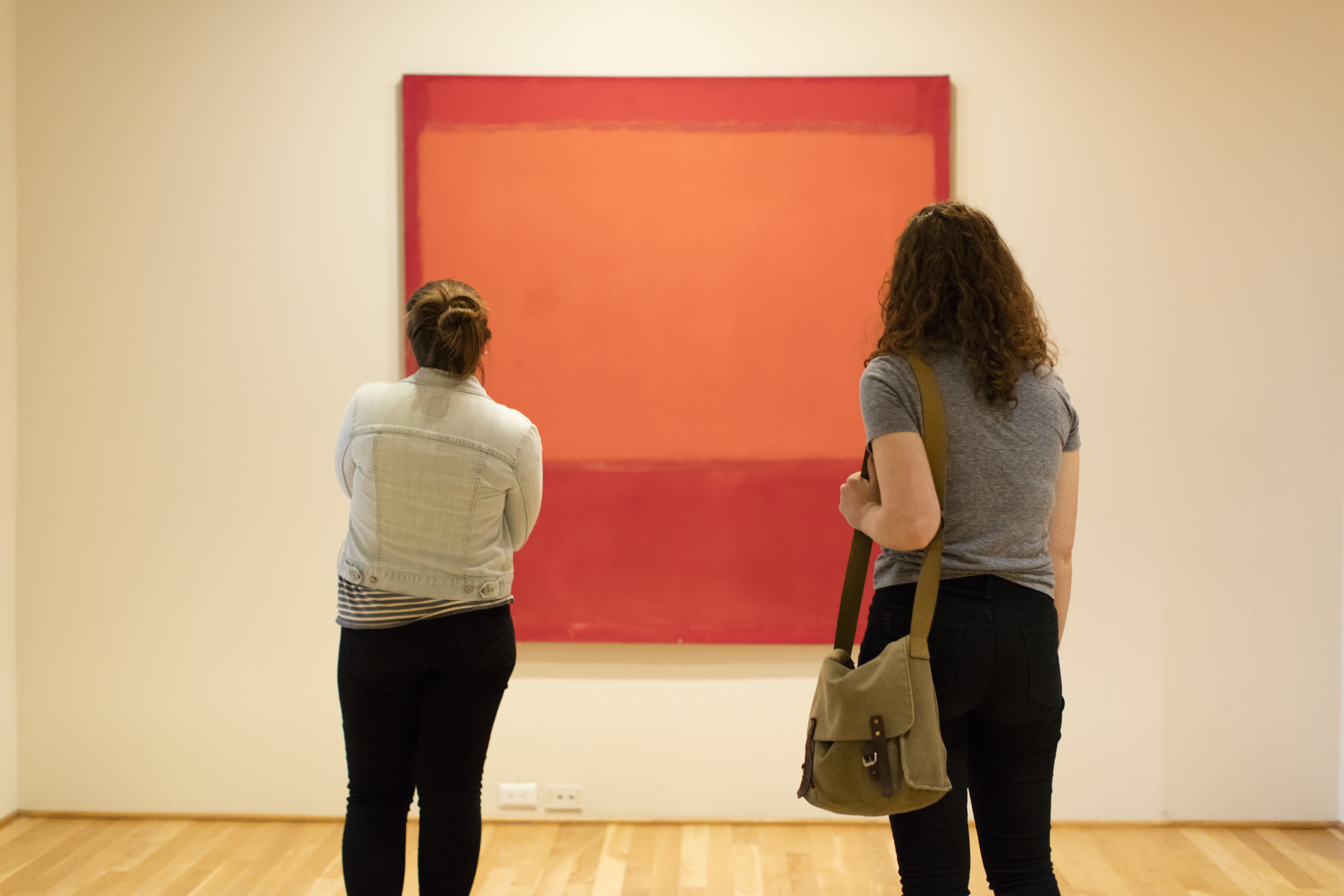 Two Gallatin students looking at a red and orange Rothko artwork in a gallery.