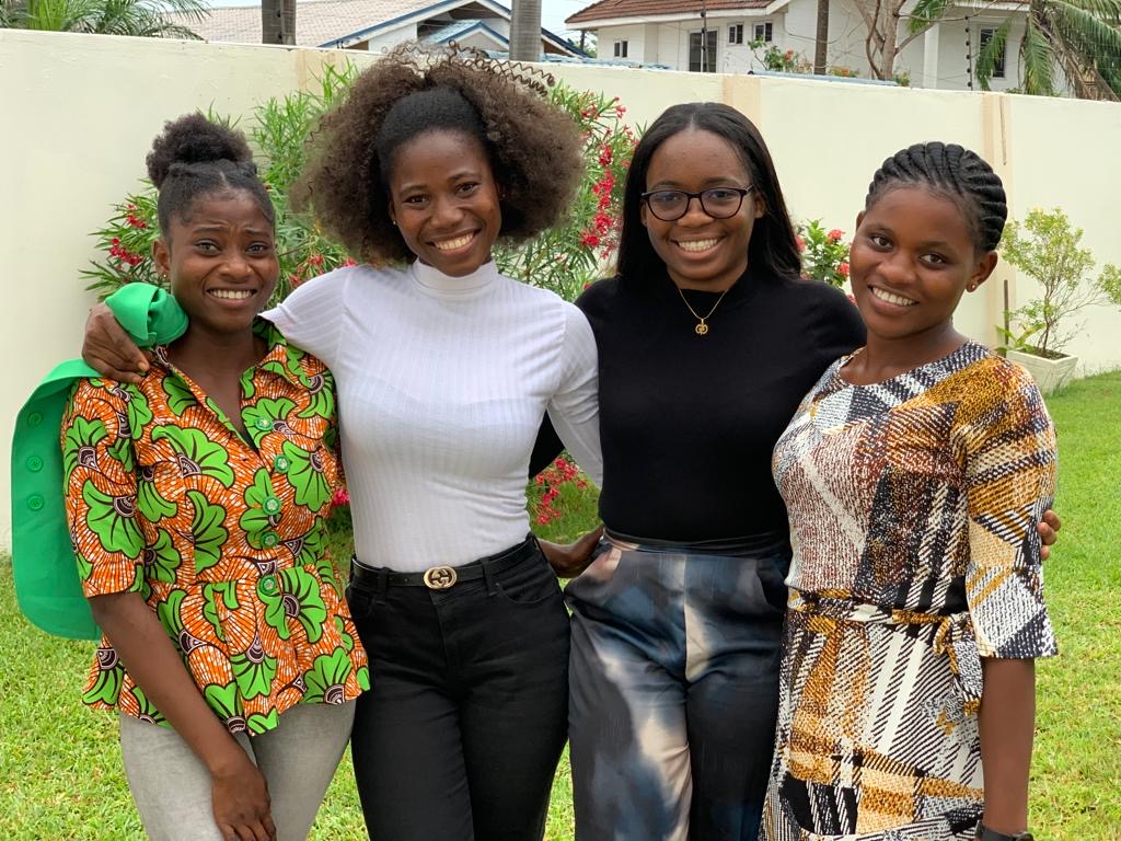 Ericka (wearing black) standing with three students from the entrepreneurship course on the day of the Pitch Competition at NYU Accra in Labone.