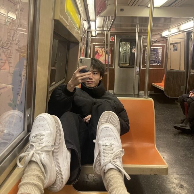 An international student takes a photo on a New York City subway car.