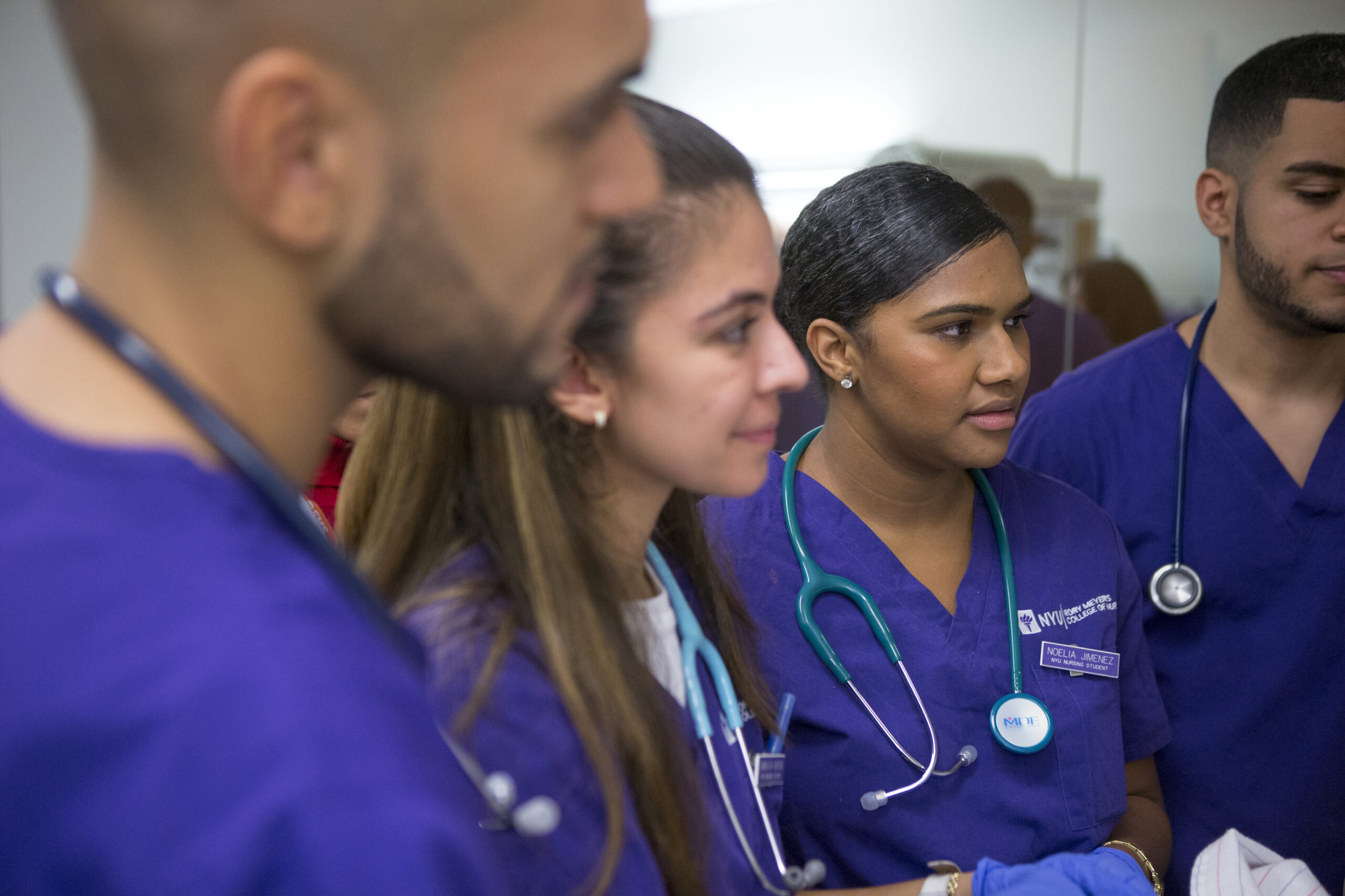 A group of students of color in purple nursing scrubs.