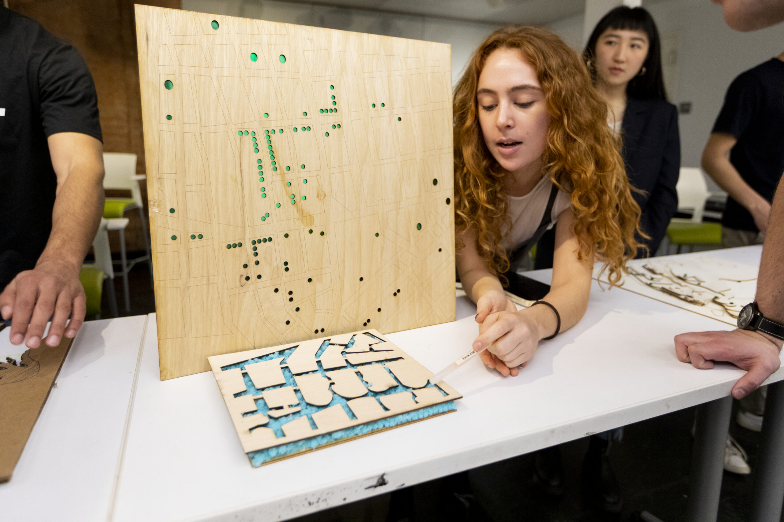 A student presenting their project, which is made from laser-cut wood.