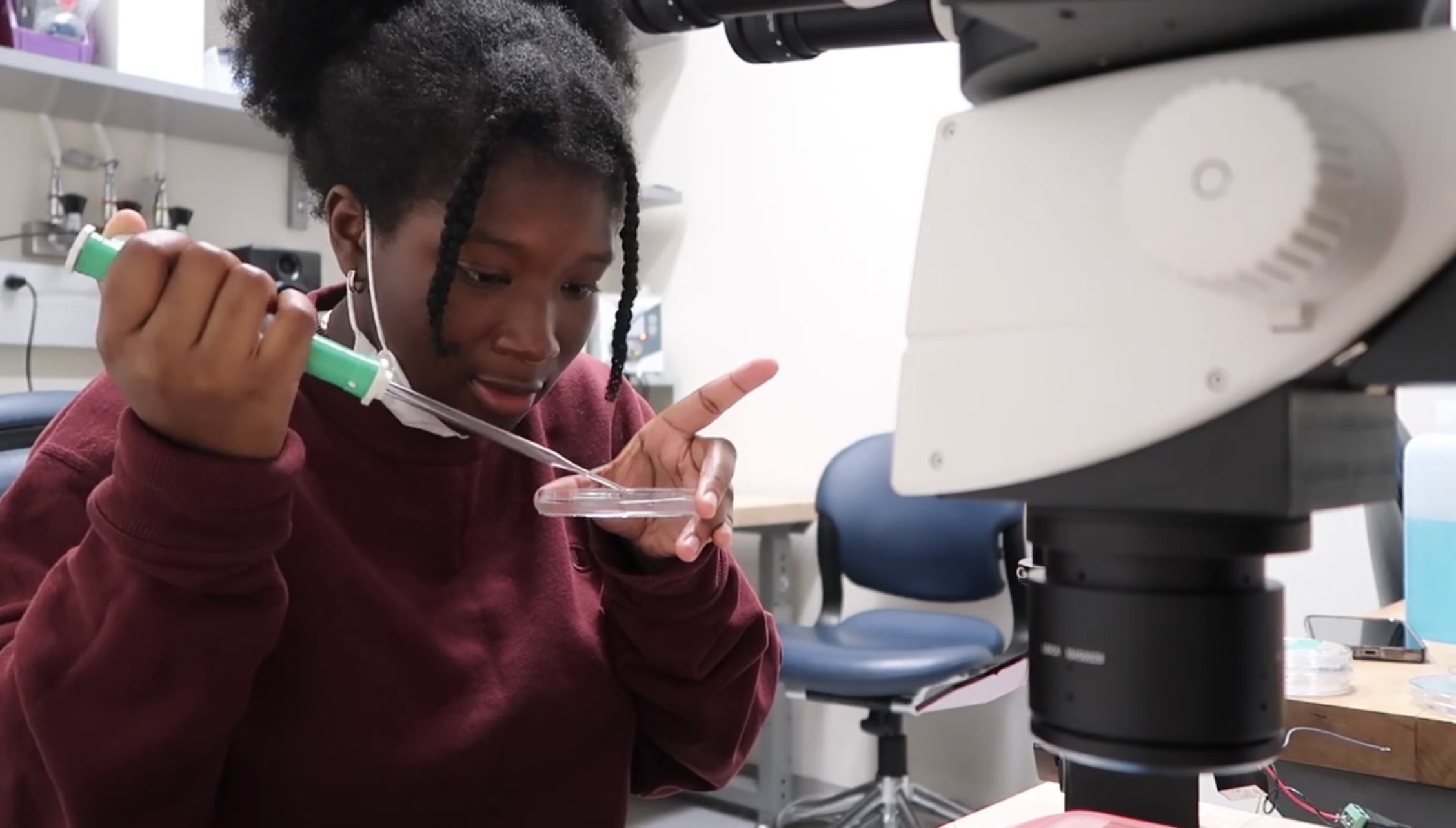A Black female student doing research in a lab.