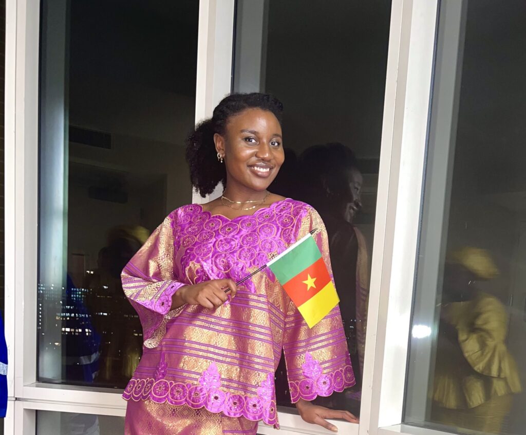 The author wearing traditional clothing, holding a small Cameroon flag. 