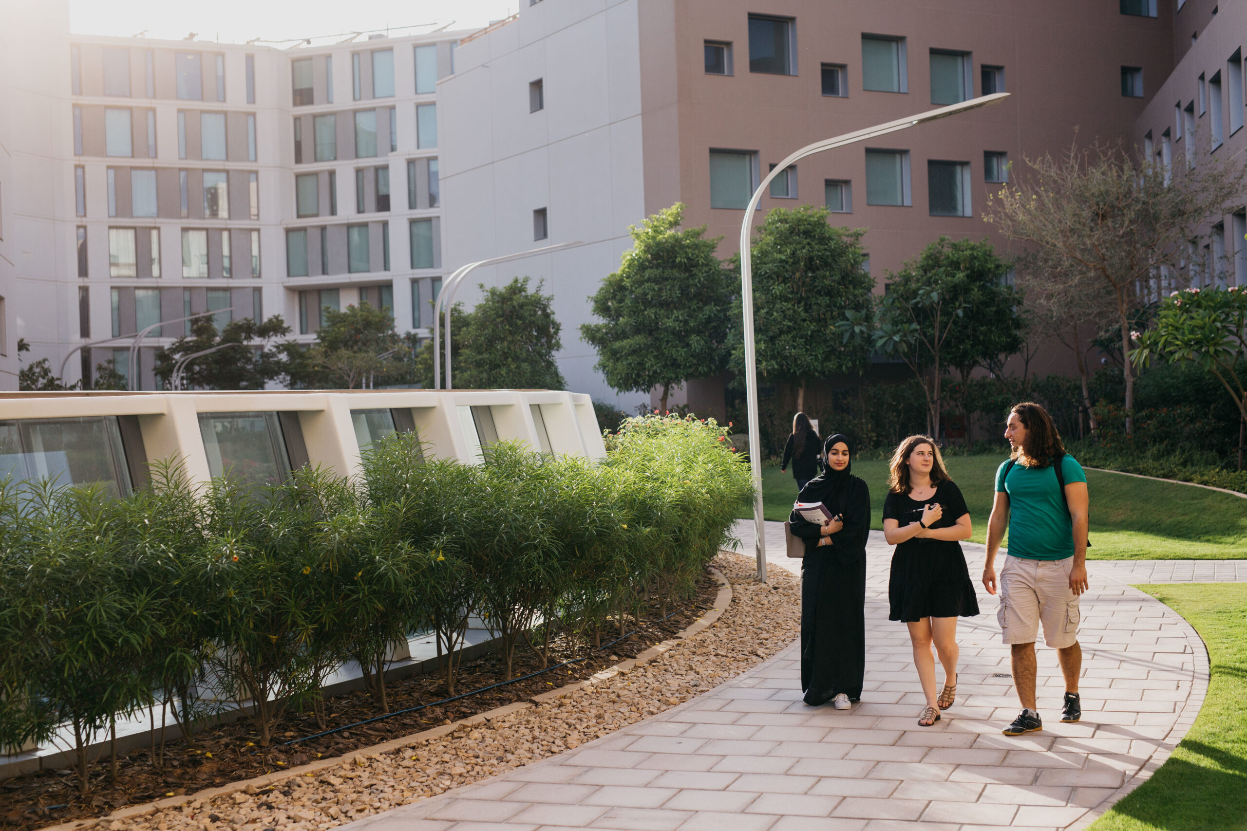Three students passing through the NYU Abu Dhabi campus.